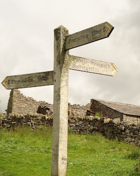 A finger post sign pointing to trails in multiple directioins