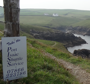 A sign saying "Take the Port Isaac shuttle service" with phone number